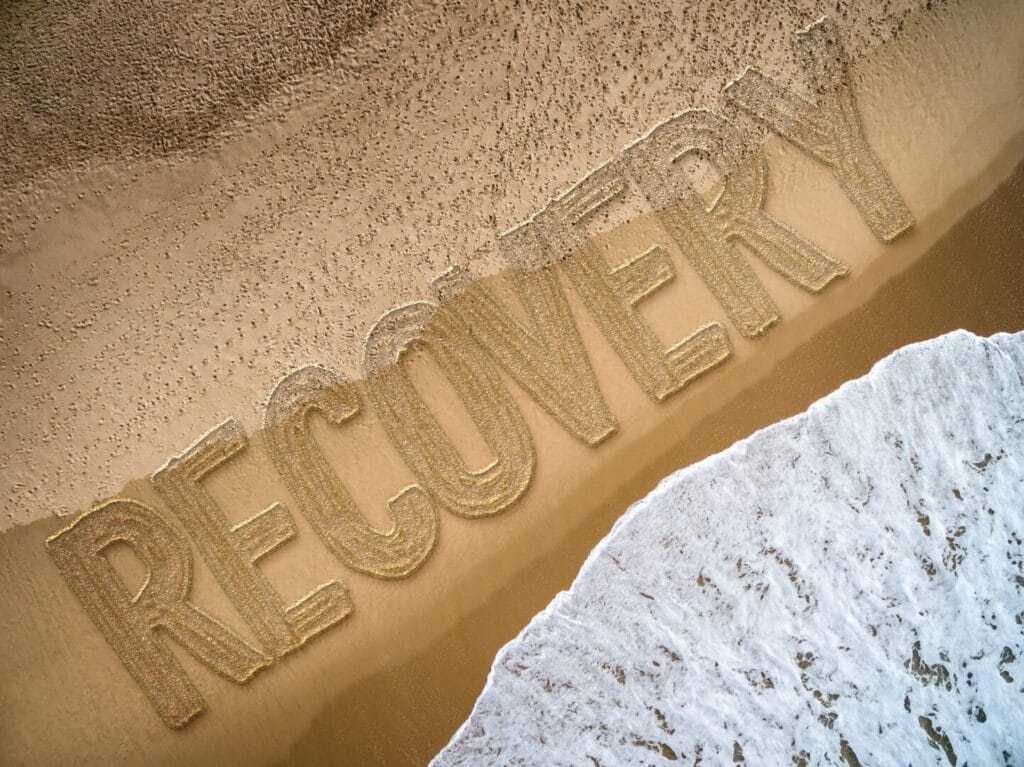 recovery written on a beach