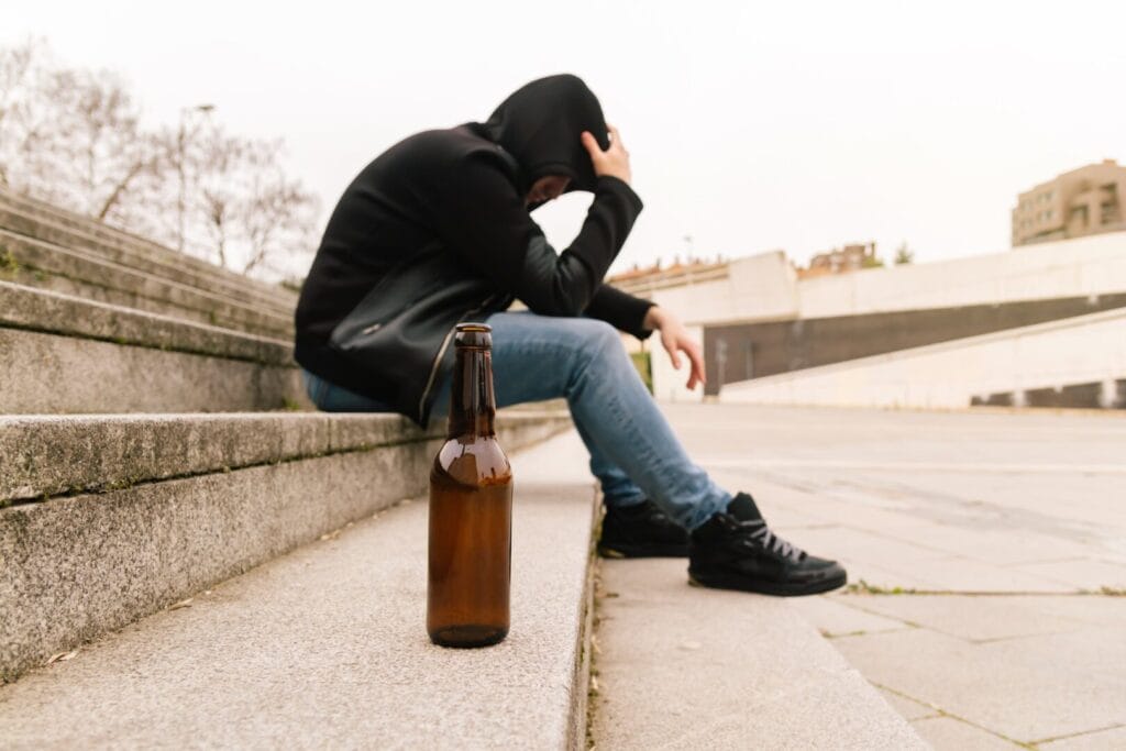 man with delirium tremens next to alcohol