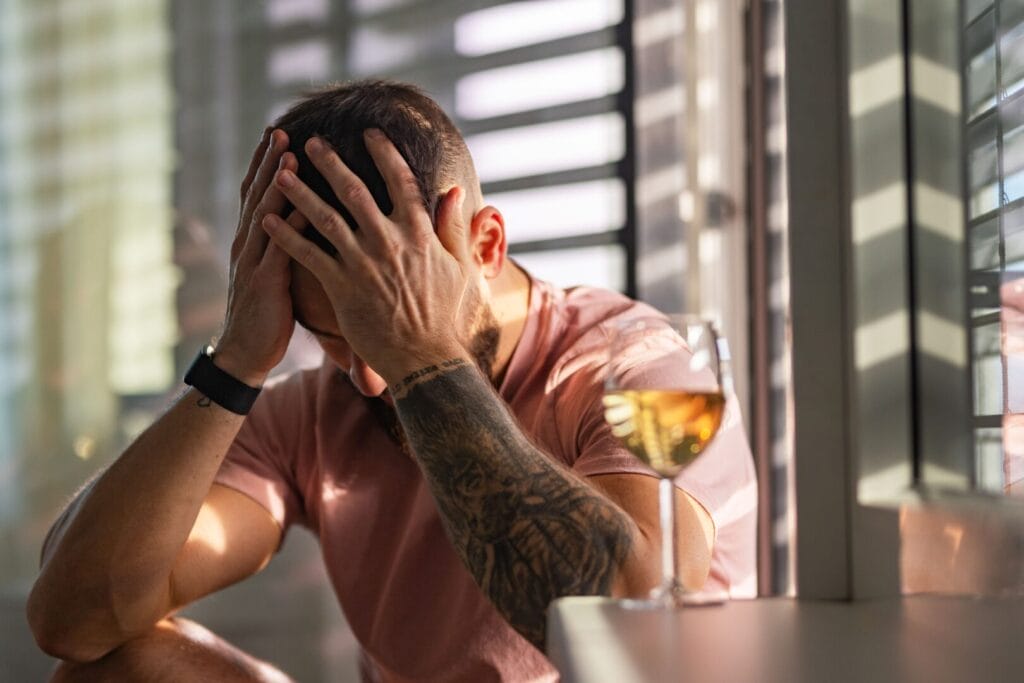 man with anxiety sitting next to alcohol